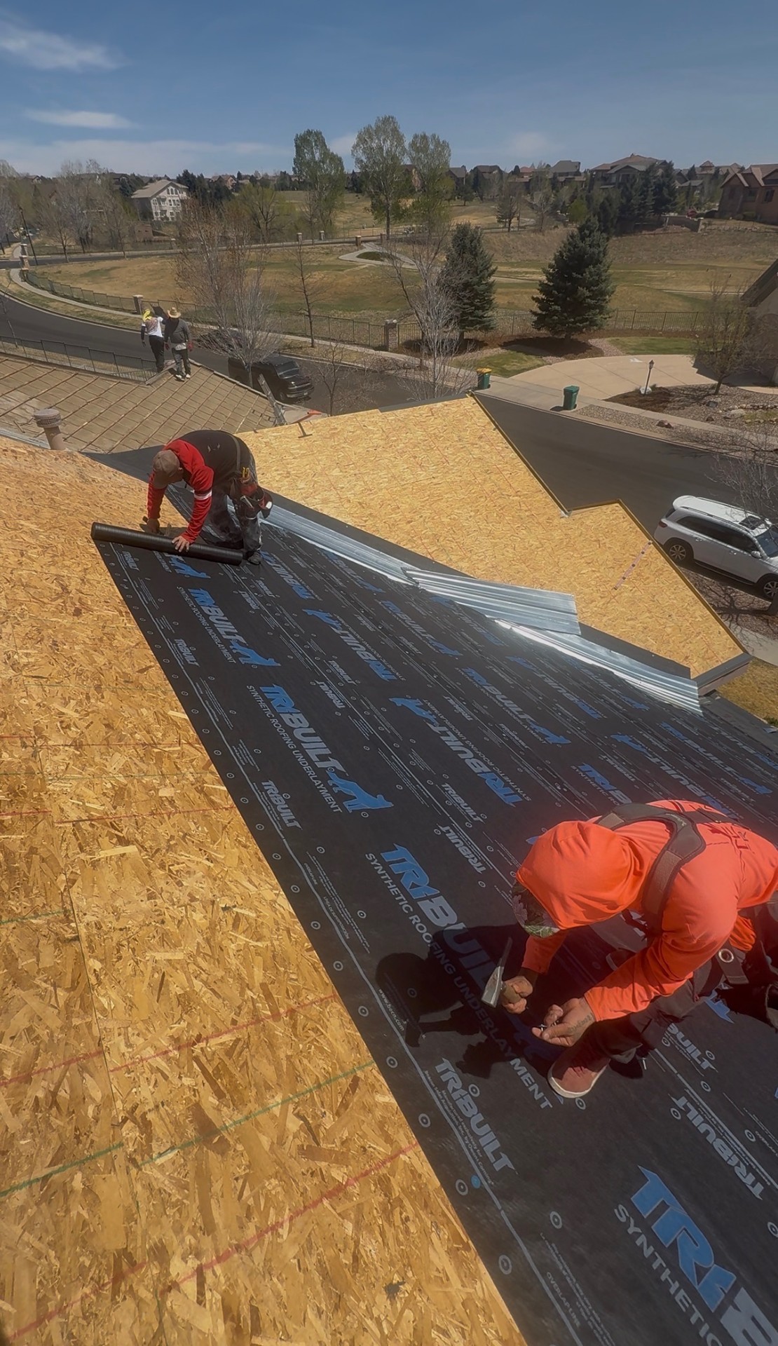 Roofing crew installing synthetic underlayment on a Colorado home
